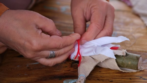 A woman makes a toy baby doll in the retro style of the Middle Ages