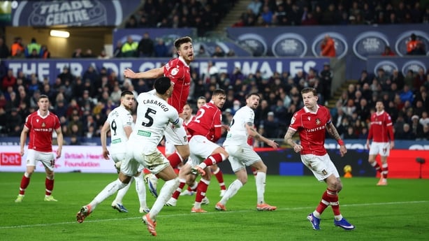 George Thomason of Wrexham heads the ball clear under pressure from Ben Cabango of Swansea City during the Sky Bet Championship match between Swansea City and Wrexham AFC at Swansea.com Stadium on December 19, 2025 in Swansea, Wales. 