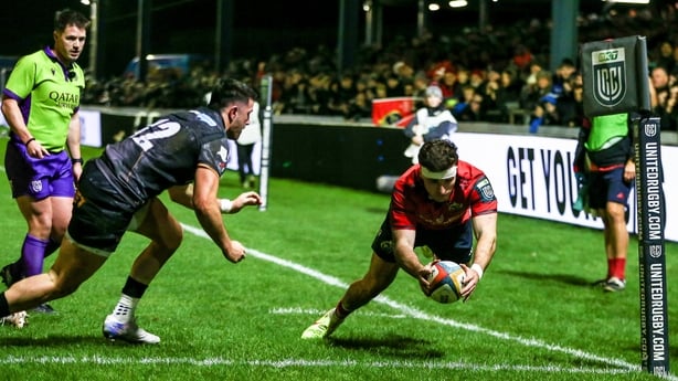 Shane Daly of Munster scores his side's first try despite the attempts of Owen Watkin of Ospreys during the United Rugby Championship match between Ospreys and Munster at Brewery Field in Bridgend, Wales