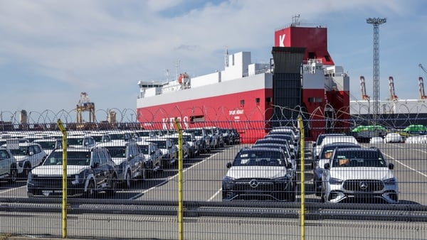 New cars parked ready for export in a German port with a ship in the background