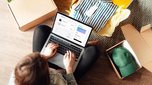Elevated view of woman making online payment via a laptop while unboxing packages from delivery