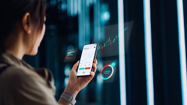 Asian businesswoman analyzing financial stock trading data on smartphone with virtual reality artificial intelligence (AI) technology. Stock exchange market trading board in background. Innovative mobile trading concept. Smart banking with technology