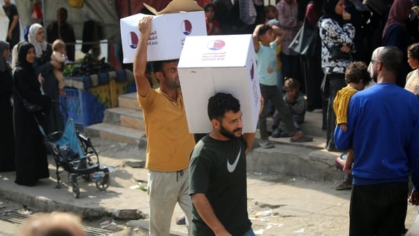 Palestinian men carry food boxes collected at a distribution centre in the in Nuseirat refugee camp - GETTY