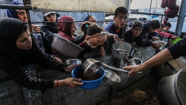 KHAN YUNIS, GAZA - DECEMBER 21: A large number of Palestinians, including children, who are struggling to access food gather in order to receive hot meals distributed by a charity organization in the Al-Mawasi area of Khan Yunis, Gaza on December 21, 2025. The food crisis in Gaza continues as Israel
