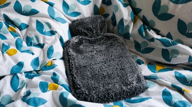 A hot water bottle on a patterned duvet cover on a bed. As energy prices rapidly increase people are looking to other ways to stay warm during the colder winter months.