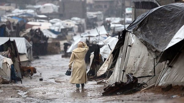 A displaced Palestinian woman walks in front of her tent following heavy rains in Gaza City