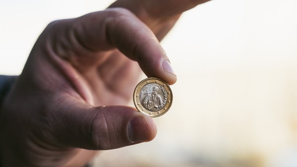 A Bulgarian one Euro currency coin held between a person's thumb and index finger