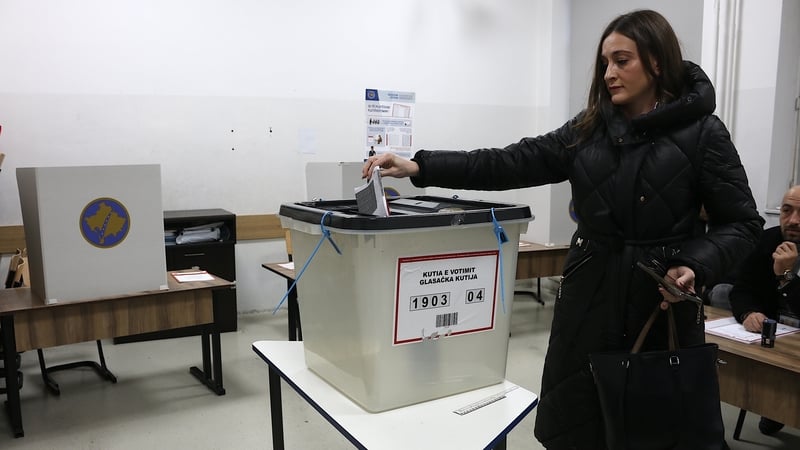 A woman casts her vote at a polling station in Pristina