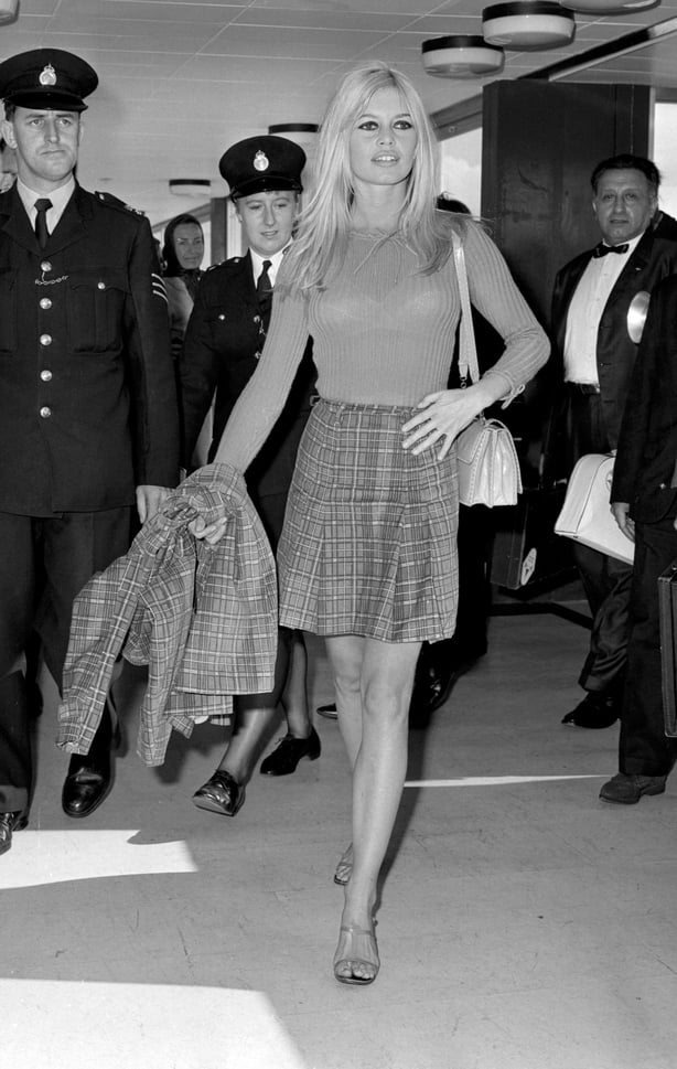 In a tartan nearly-mini skirt and carrying a matching jacket, French actress Brigitte Bardot arrives at London Airport to film the Anglo-French 'Two Weeks in September' in which she plays a French model.