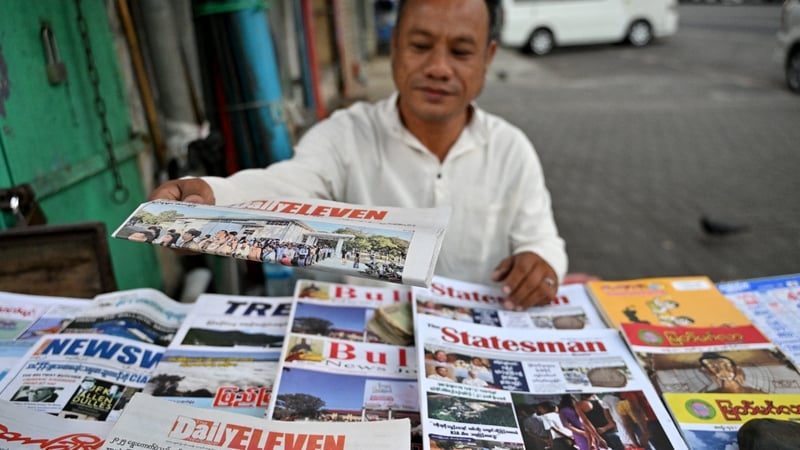 A vendor arranges newspapers reporting on Myanmar's general election in Yangon on December 29, 2025