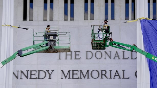Workers affix signage adding US President Donald Trump's name on the facade of the Kennedy Center in Washington, DC, US, on Friday, Dec. 19, 2025. The board of the John F. Kennedy Center for the Performing Arts voted Thursday to rename Washington's premier arts venue after President Donald Trump as 