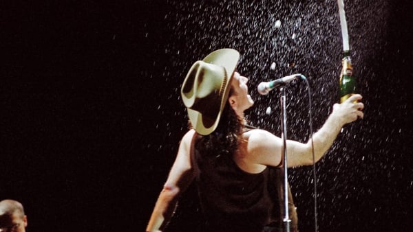LONDON, UNITED KINGDOM - JUNE 12: Bono of U2 sprays the crowd with champagne while performing on stage at Wembley Stadium on June 12th, 1987 on 'The Joshua Tree' tour in London, England. (Photo by Pete Still/Redferns)