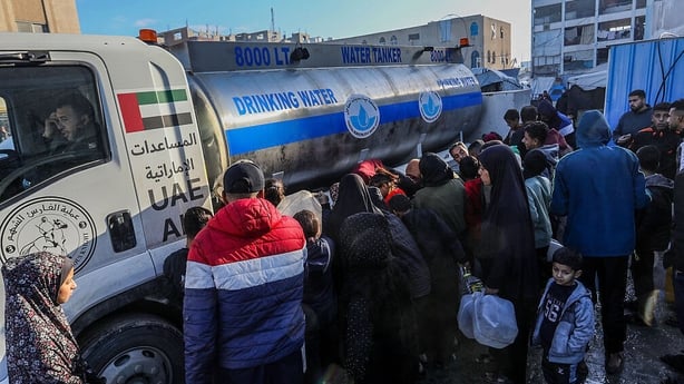 Palestinians gather to receive drink water distributed from water tankers