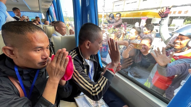 Cambodian soldiers, who had been captured by Thai soldiers in July, gesture to well-wishers from a bus after their release