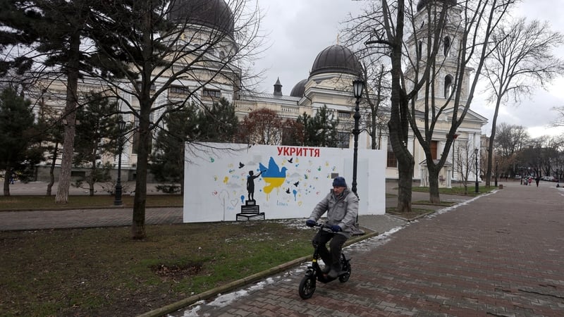 A man rides an electric bike past a new mobile shelter in front of the Transfiguration Cathedral in Odesa