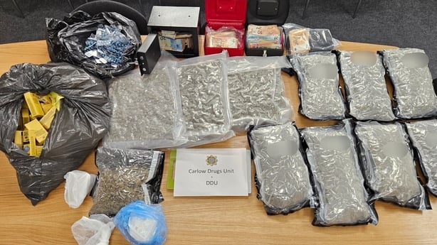 Cannabis, cocaine, tablets, vapes and cash on a table