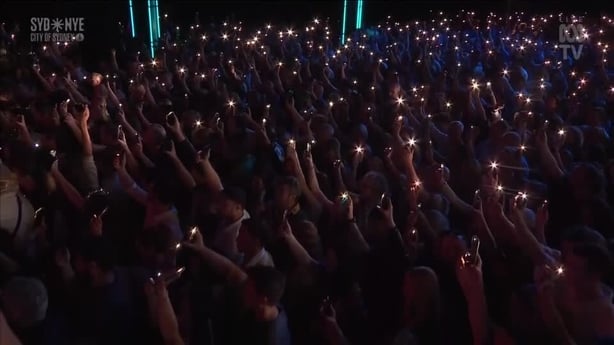 Hundreds of people hold lights aloft 