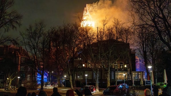 People look at the tower of the Vondelkerk church on fire
