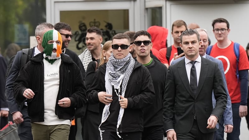 Kneecap's Liam Óg Ó hAnnaidh (centre, in keffiyeh), with his lawyer Darragh Mackin, and bandmates J.J. Ó Dochartaigh (left) and Naoise Ó Cairealláin (back right) outside Woolwich Crown Court, London last year