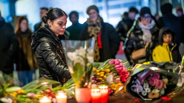 A woman lays flowers at a floral tribute site