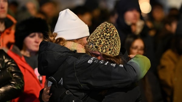 Mourners gather to leave flowers and candles at the scene after a fire broke out overnight at Le Constellation bar