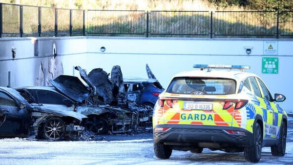 A garda car beside a row of burnt cars