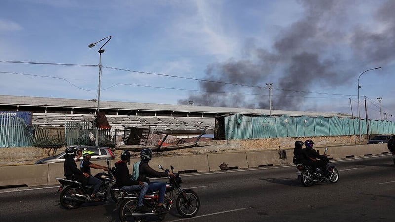 People drive along a highway past a damaged area of Port of La Guaira