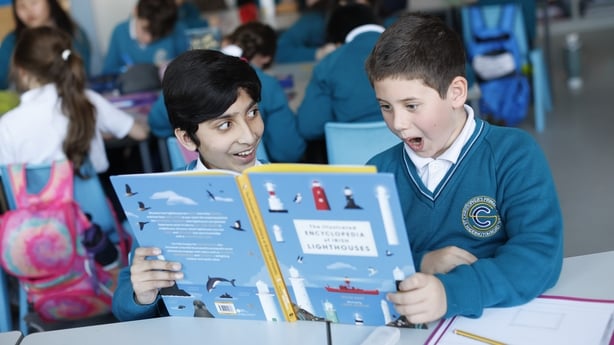 Two boys react as they hold a book