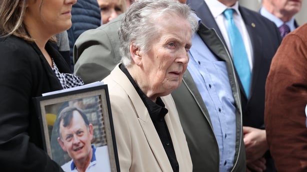 a woman holds a photo frame with and older woman standing beside her