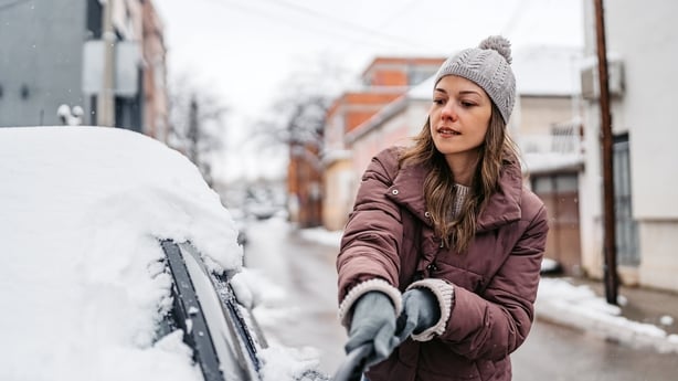 woman cleaning snow off her car