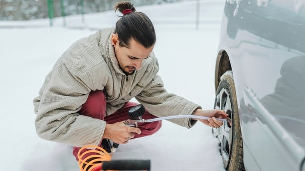 Young man checking Tire Pressure during winter