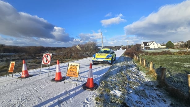 A garda car parked on a snowy road in County Donegal behind a sign that reads Road Closed
