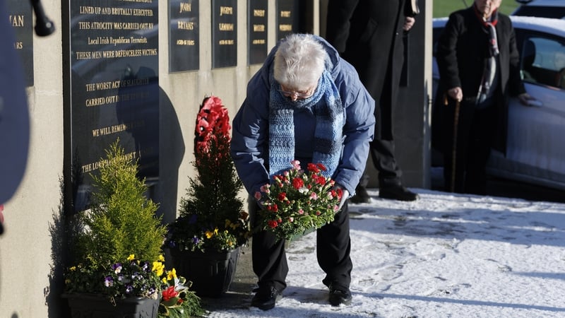 May Quinn, sister of victim Robert Walker, lays a bouquet of flowers at the Kingsmill Memorial Wall