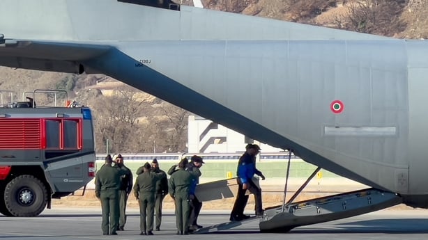 Swiss police officers carry a coffin onto a plane