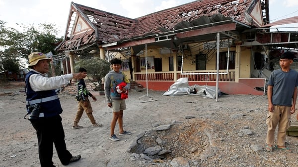 People stand beside a crater in front of a damaged police station following clashes between Cambodian and Thai soldiers in Boeung Trakoun village in Banteay Meanchey province on January 3, 2026