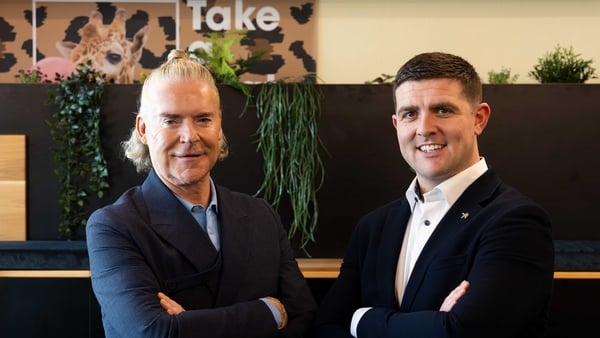 two men in suits smiling in an office setting