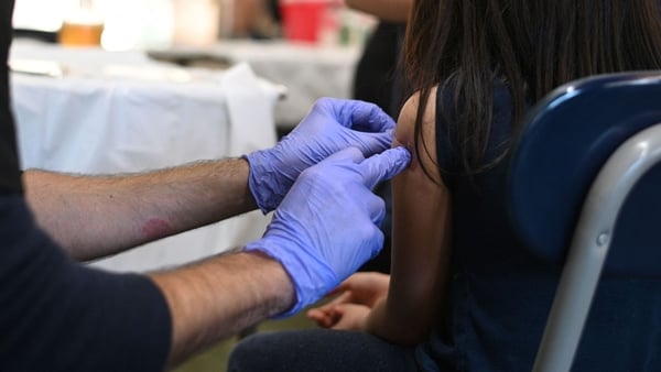 a person wearing surgical gloves puts a plaster on a girl's arm