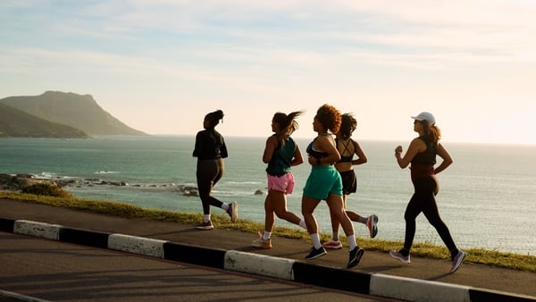 Five young women athletes are running by the sea at sunset, enjoying a healthy lifestyle