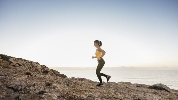Woman running outdoors on a coastal trail, exercising in active lifestyle