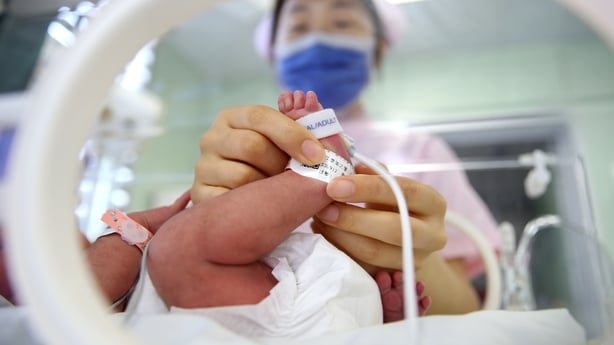 A nurse holds a baby's foot in the neonatal department of a hospital