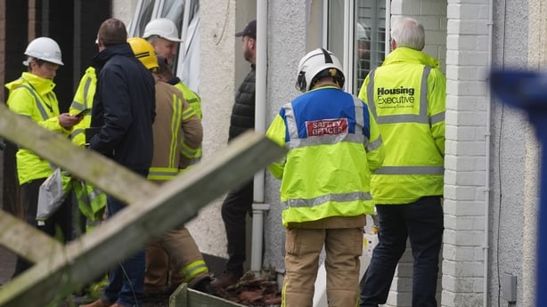A safety officer and members of the Housing Executive at the scene of an explosion at a property on the Lower Braniel Road