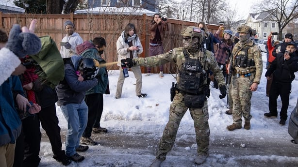 A Border Patrol Tactical Unit agent sprays pepper spray into the faces of bystanders attempting to block an immigration officer
