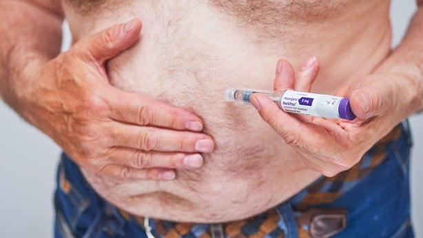 A man injects himself in the stomach