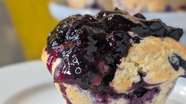 A lemon and blueberry muffin topped with blueberry sauce