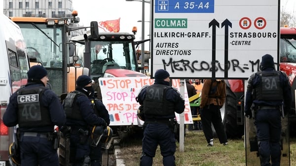 French police officers stand guard in front of farmers taking part in a demonstration against the Mercosur agreement