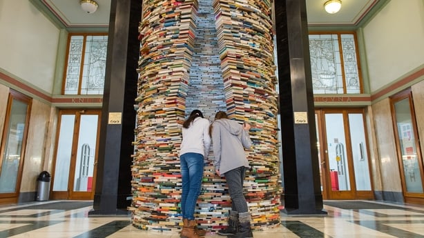 People look inside of Idiom installation, created by Slovakian artist, Matej Kren. The Idiom installation, is a cylindrical tower made of books 