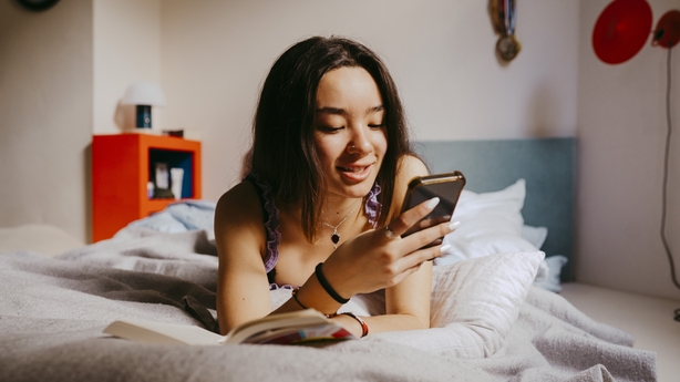 A young woman using her phone in bed