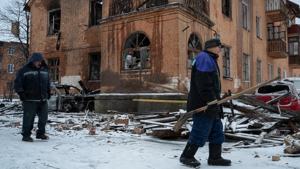 Municipal workers walk past a three-story residential building in the Dniprovskyi district damaged by Russia's large-scale overnight strike in Kyiv, Ukraine