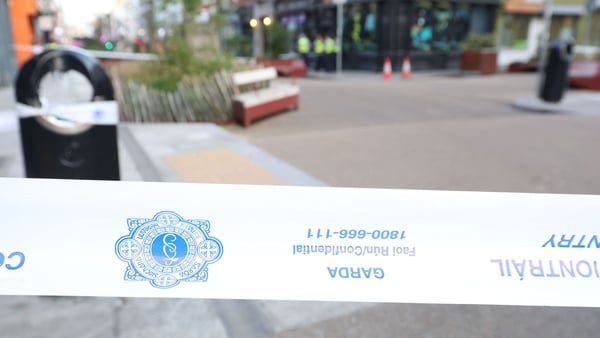 a garda crime scene tape with a street view in the background