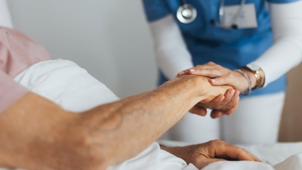 Close-up of caregiver holding senior client hand. Support from nurse to patient, taking care of elderly man in hospital. Emotional support and care in healthcare, hospice care.